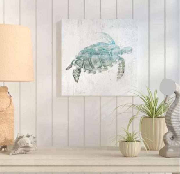 A tropical sea turtle painting on a table next to a lamp.