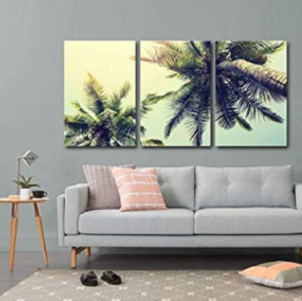 Three tropical palm trees on a wall in a living room.