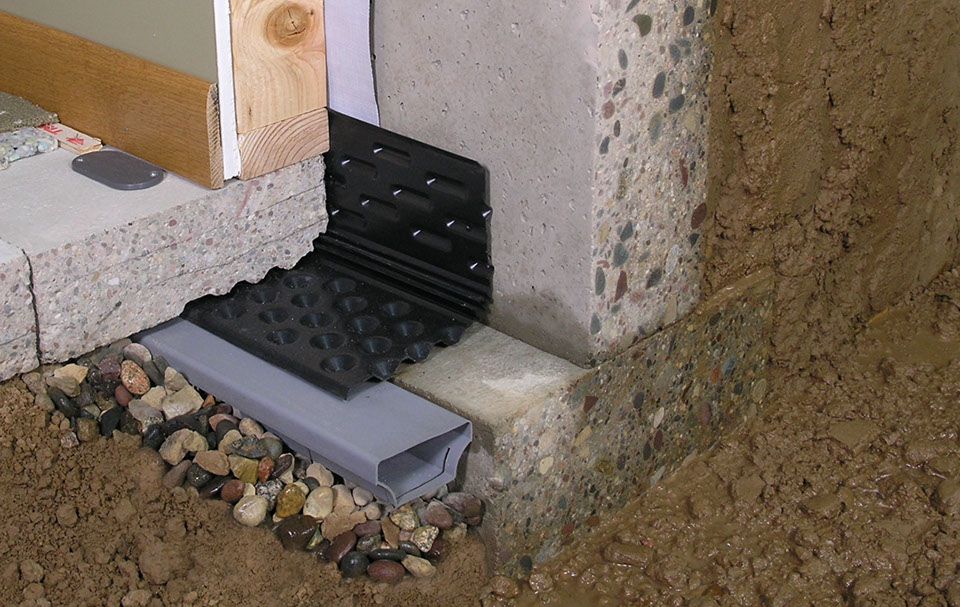 A concrete wall with a drain pipe for basement waterproofing.
