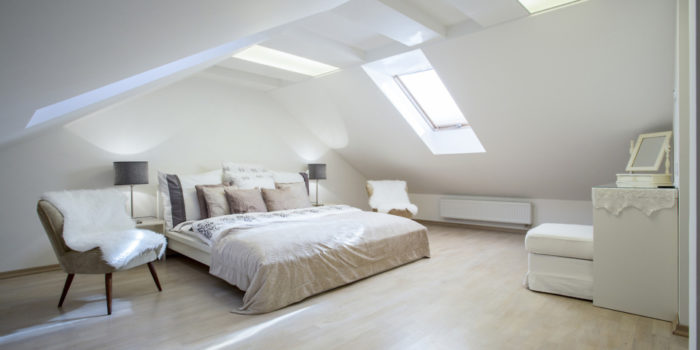 An attic bedroom with windows and a bed.