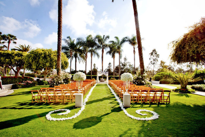 A San Diego wedding ceremony set up in a grassy area with palm trees.