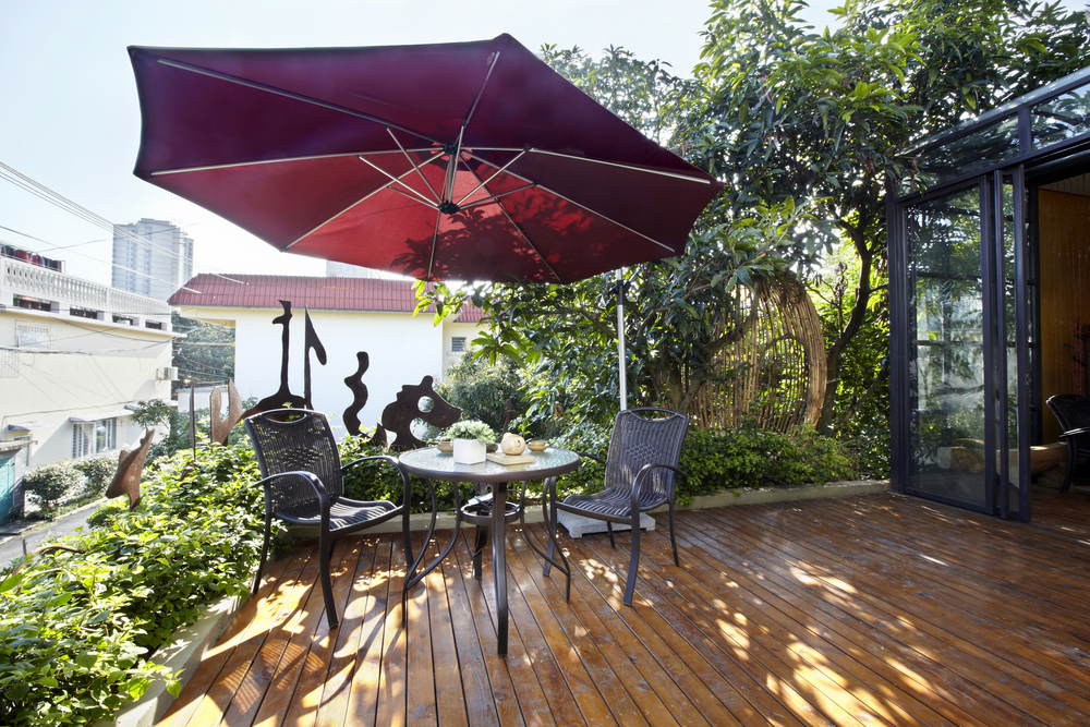 A red umbrella on a wooden deck with a flat roof.