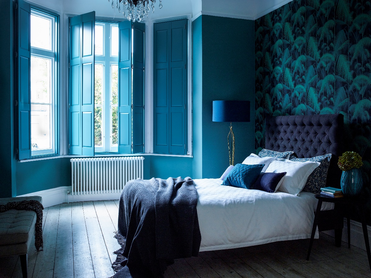 An affordable bedroom with blue walls and wooden floors.