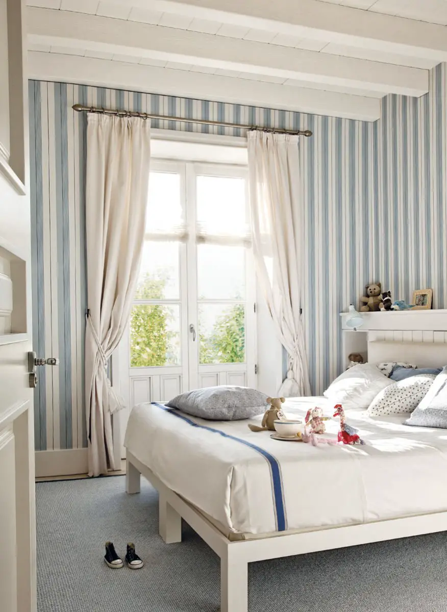 A bedroom with blue and white striped walls and curtains.