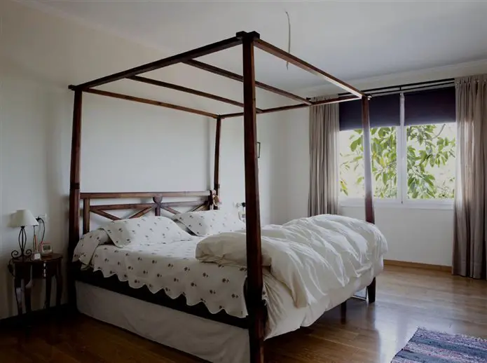 A renovated bedroom with a four poster bed and wooden floors.