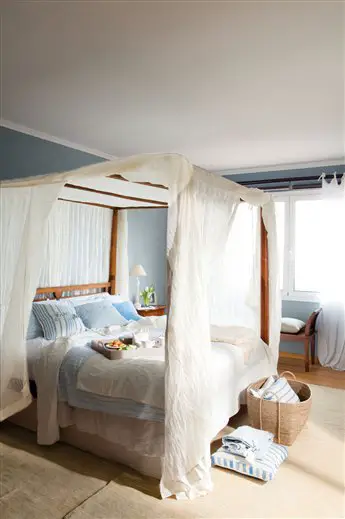 A renovated bedroom with a white canopy bed and blue walls.
