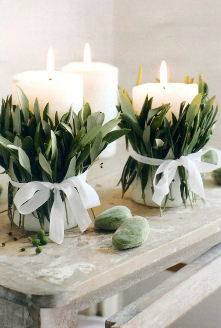 A serene spa ambiance with two candles and eucalyptus leaves on a table.