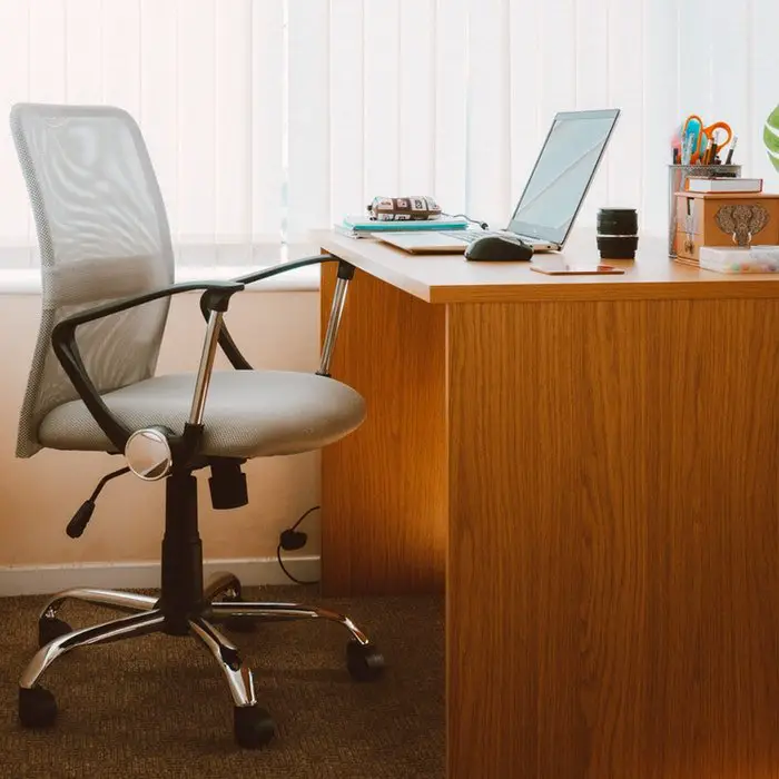 A desk with a chair and a laptop, perfect for home offices.