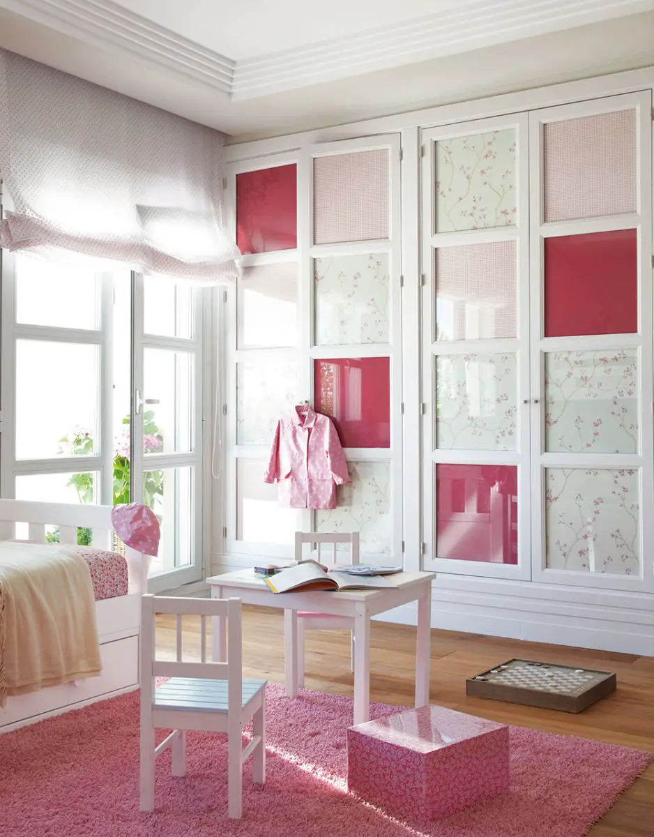 A pink and white children's room with white furniture and curtains.