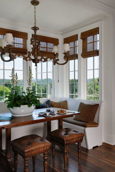 A dining room with wooden chairs and window treatments.