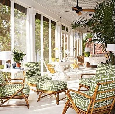 A tropical screened in porch with wicker chairs and a fan.