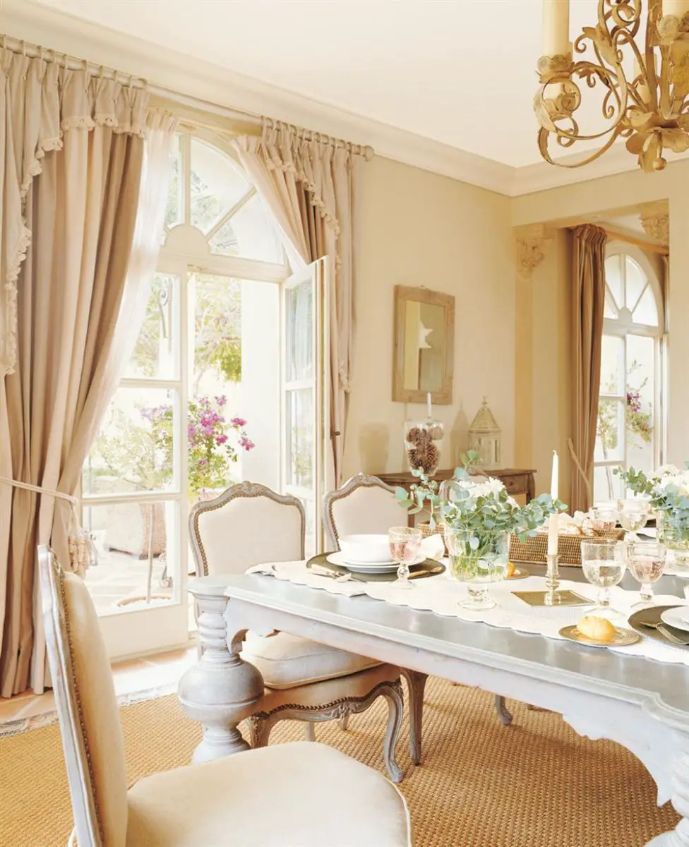 A dining room with white table and chairs, curtains.