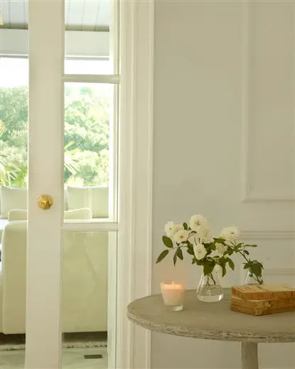 A home decor featuring a white table with a vase of flowers in front.