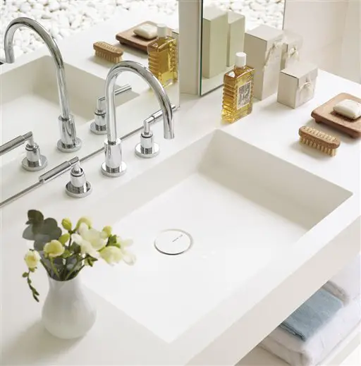 A white sink and soap dispenser in a home bathroom.