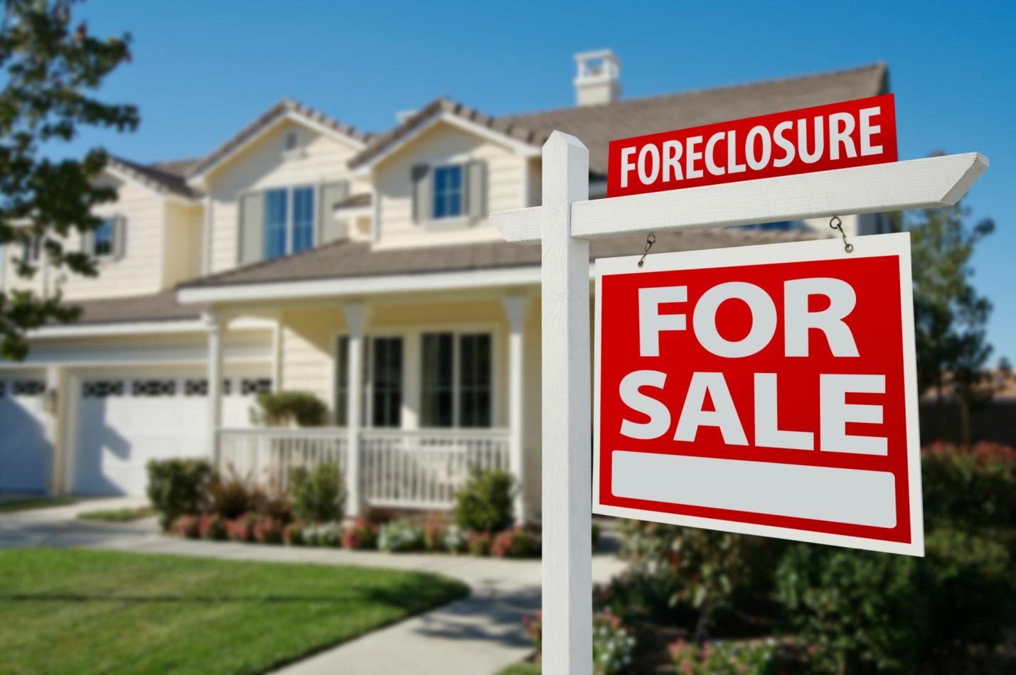 A "For Sale" sign in front of a house available for purchase.