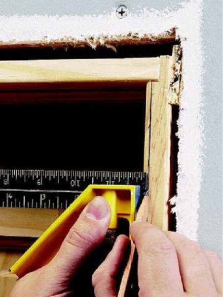 A person measuring a hole in a door using a ruler.