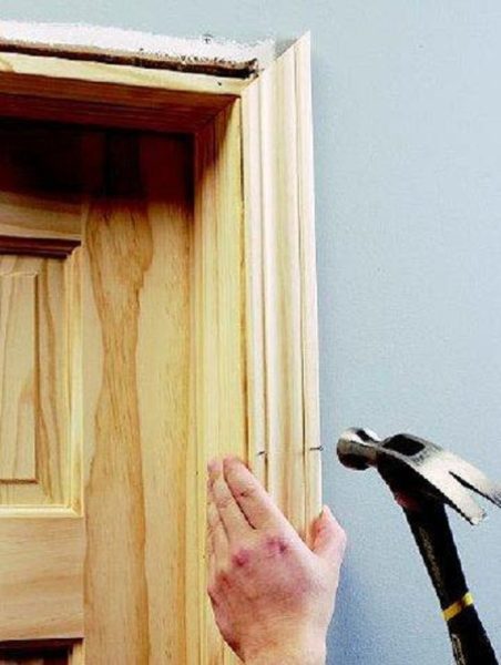 A person is hammering a piece of wood into a door.