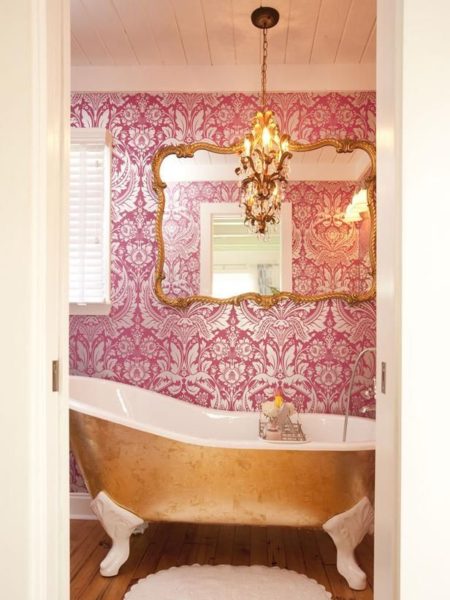 A pink and gold bathroom with gold tub and furniture.