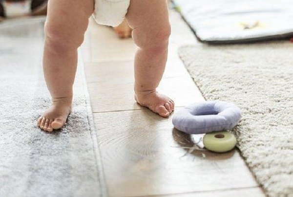 A baby playing on the floor with a toy in a children's room.
