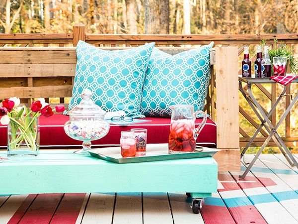 A patio with pallets transformed into a cozy couch, adorned with pillows and drinks.