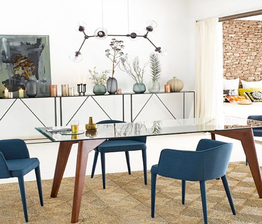 A modern dining room at home with blue chairs and a glass table.