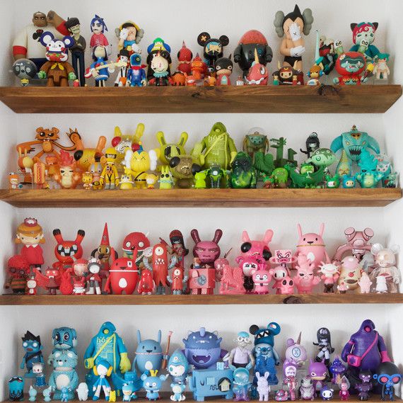 A shelf full of collectible toy figurines on a wooden shelf.