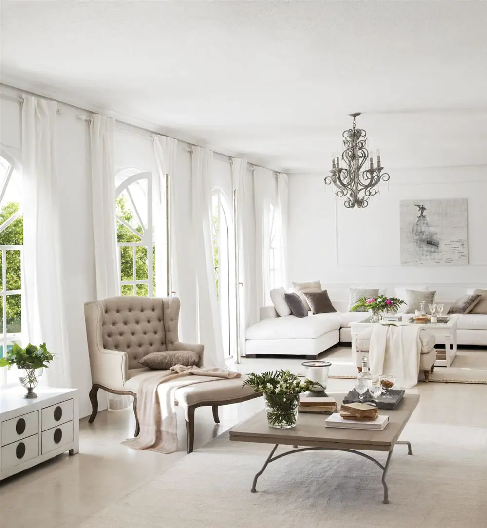 A white living room with curtains and a chandelier.
