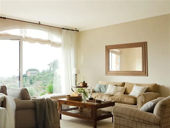 A living room with beige furniture and a large window undergoing renovation.
