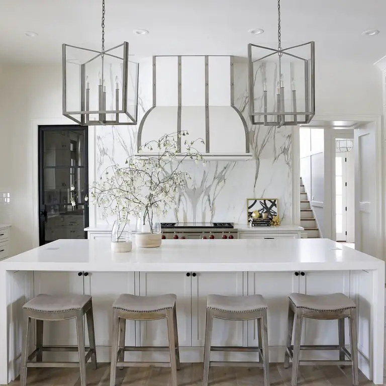 A kitchen with white and marble counter tops.