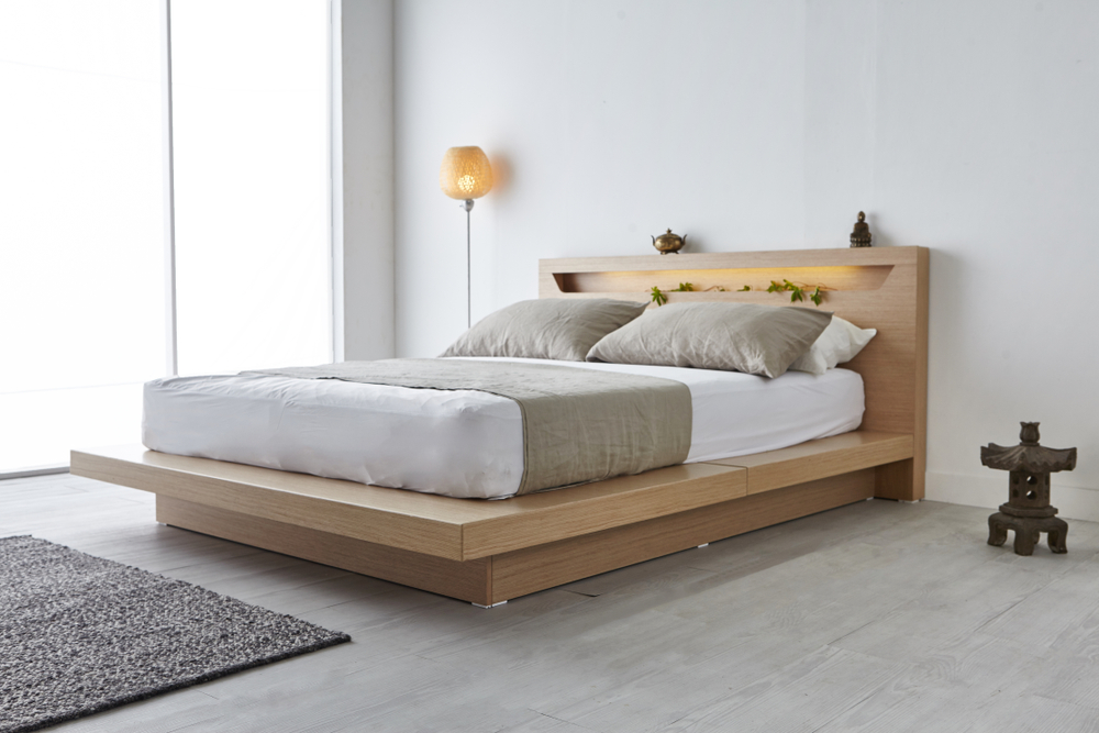 A wooden bed frame with an upgraded mattress in a bedroom.