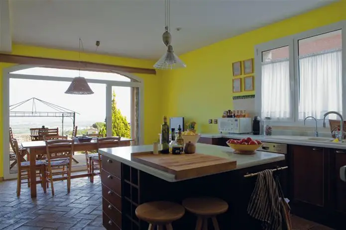 A renovated kitchen with yellow walls and a table and chairs.