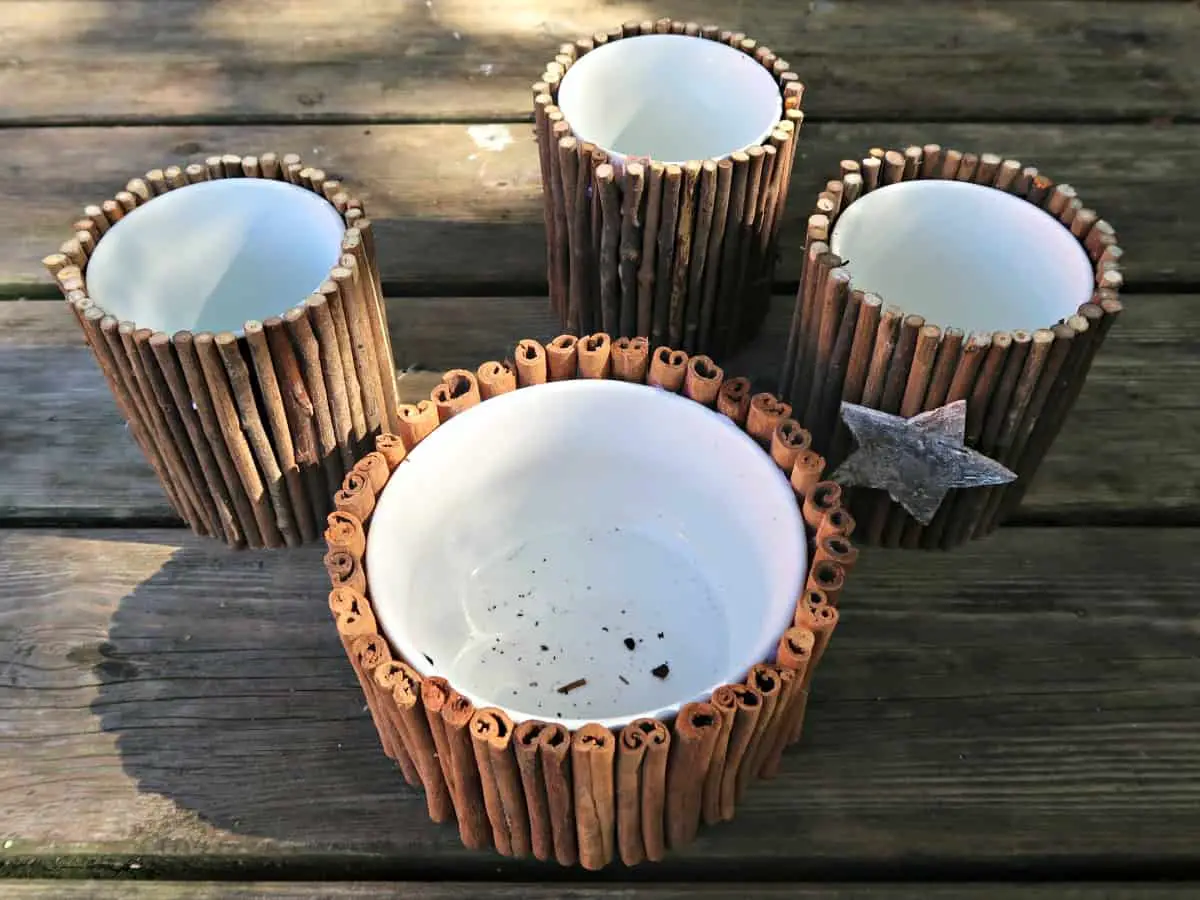 Three sustainable candle holders made from sticks on a wooden table.
