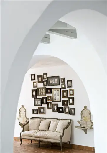 An archway with a couch and framed pictures in a home.