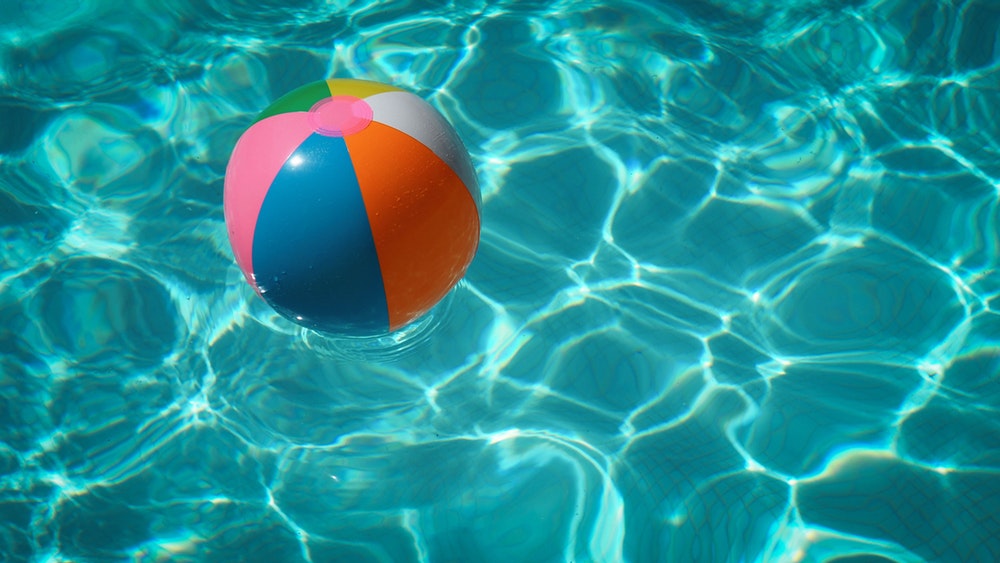 A colorful beach ball floating in a swimming pool.