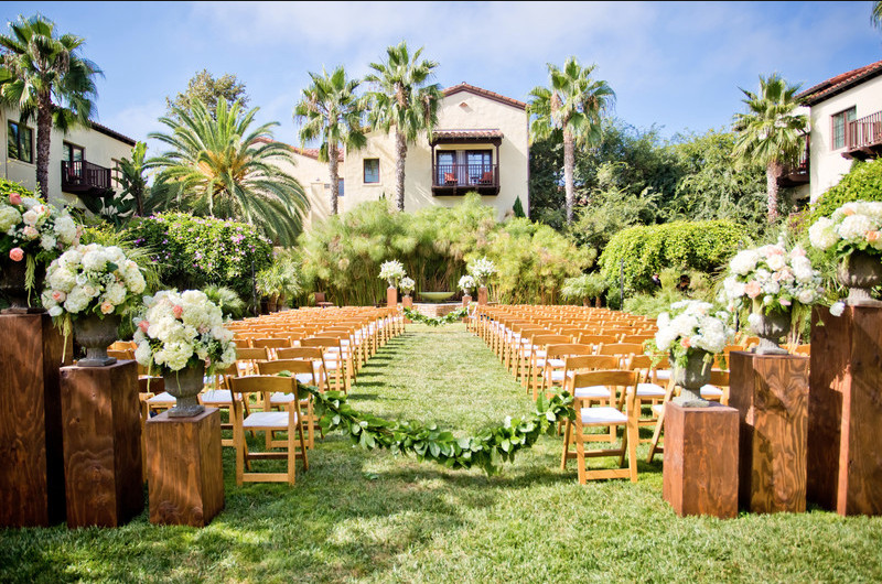 An outdoor San Diego wedding ceremony set up with wooden chairs and flowers.