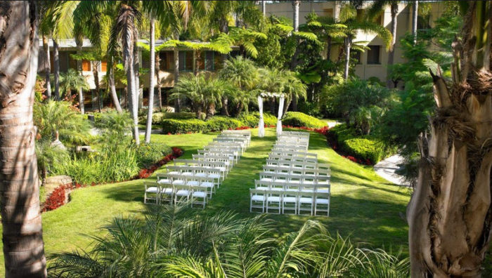 A San Diego wedding ceremony set up in a garden with palm trees.