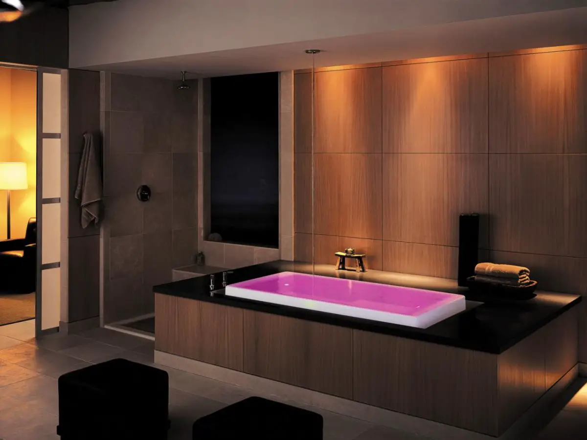 A modern bathroom with a pink bathtub and a bathroom shelf.