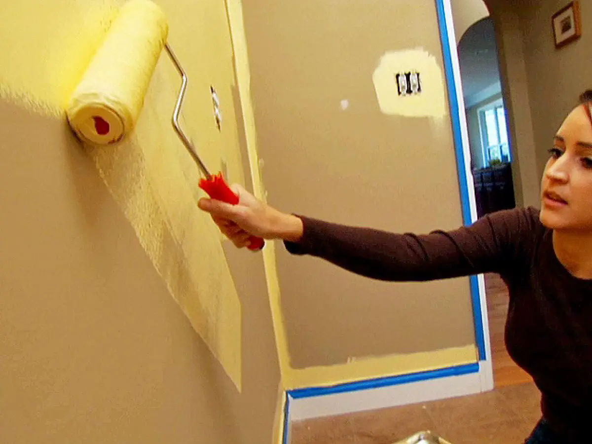 A woman painting a yellow wall in her house.