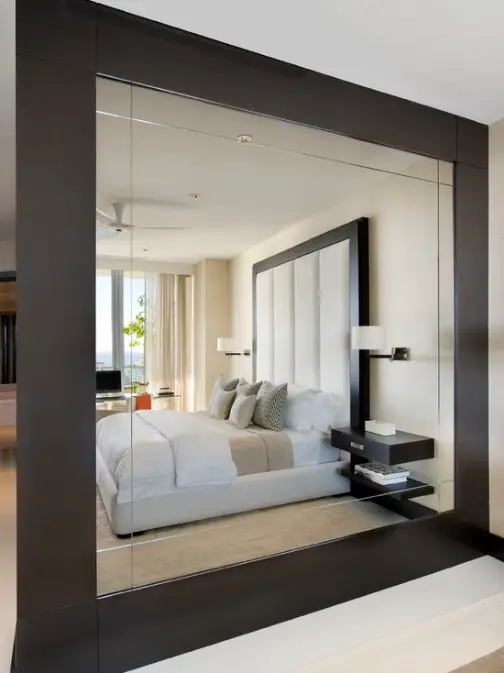 A bedroom with a spacious layout and a large mirror.