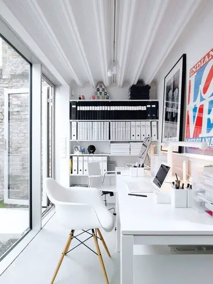A spacious white home office with a large window.