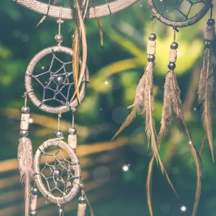 A boho chic decoration featuring a dream catcher adorned with feathers.