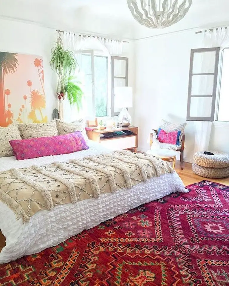 A boho chic bedroom with a colorful rug on the floor.