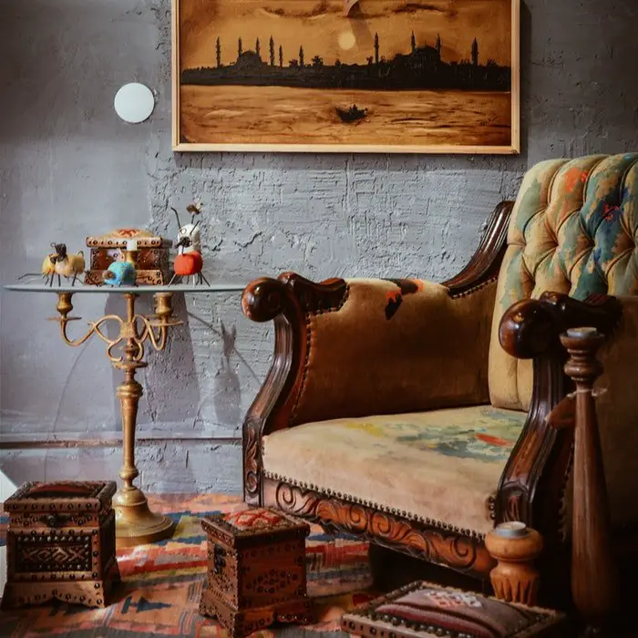 A wooden chair in a room with a painting on the wall.