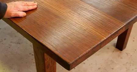 A person's hand is touching a table made of wood.