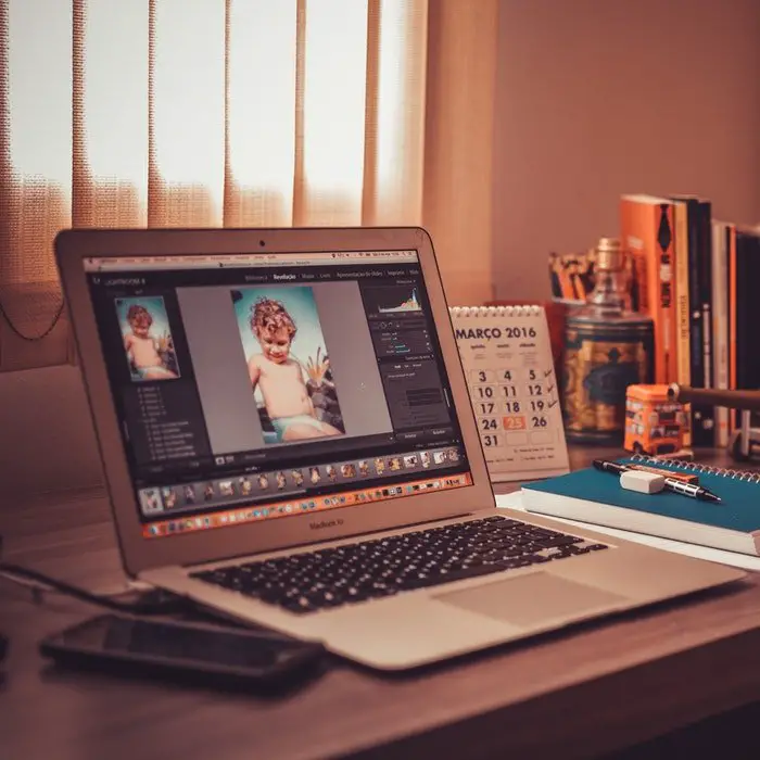 A laptop on a desk in a home office with a photo on it.