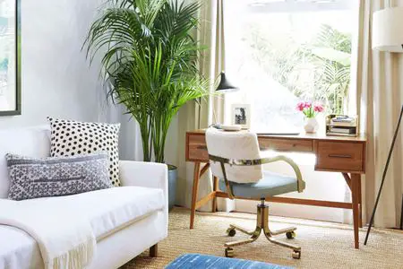A home office with a white couch and a chair.