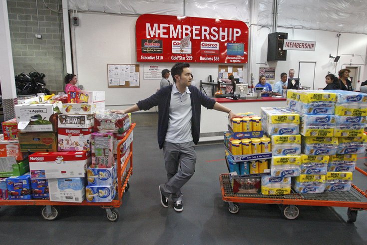 A man navigating through a warehouse filled with carts overflowing with products.