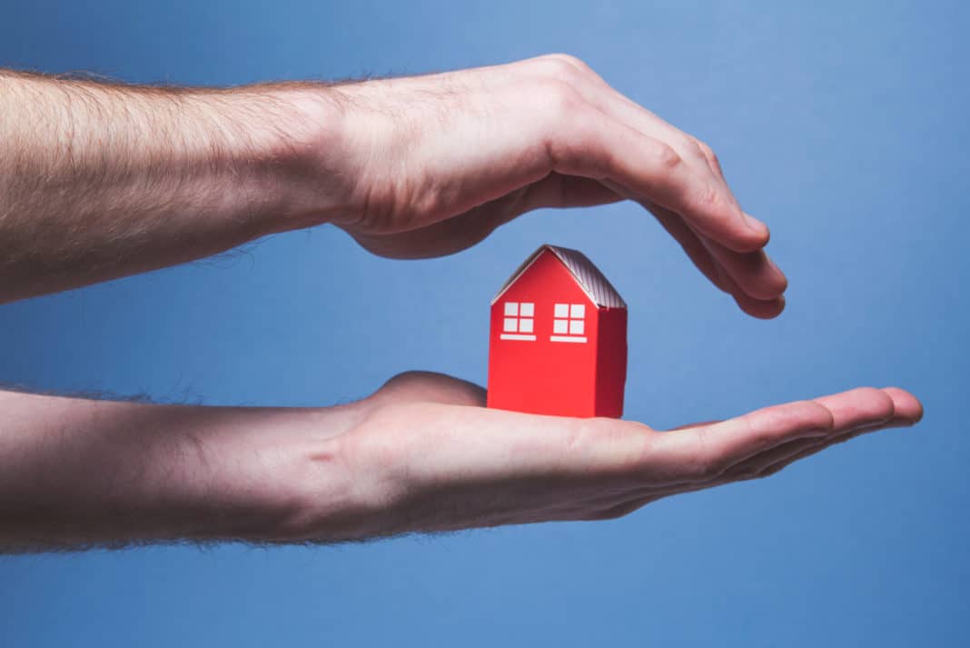 Keywords: Home Warranty Plan

Description: A man's hand holding a red house on a blue background, emphasizing the importance of choosing a home warranty plan.
