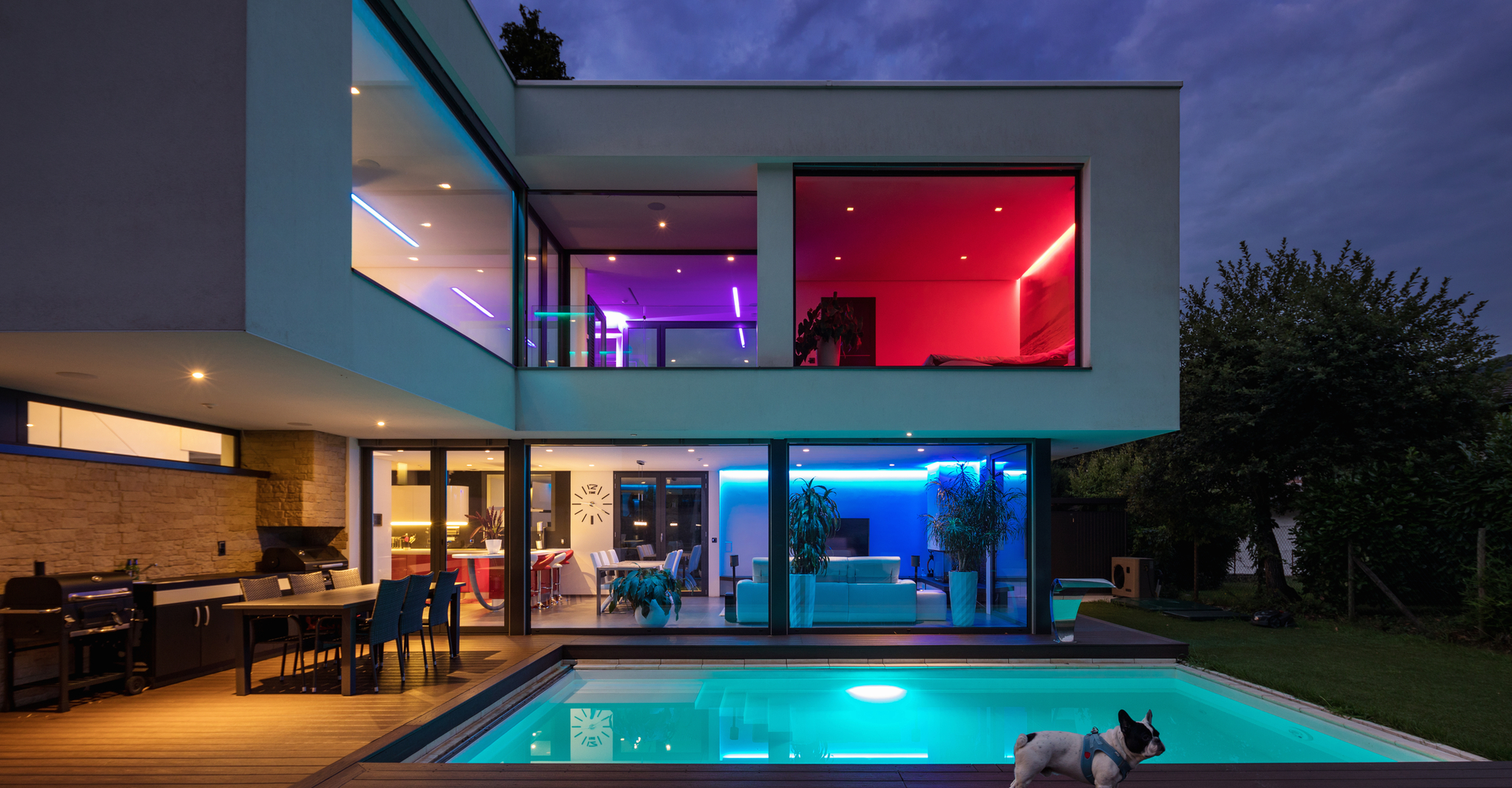 A modern house with a pool and colorful lights equipped with external LED lighting to keep the party going.