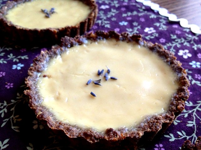 Two lavender-infused chocolate tarts plated on a purple cloth.